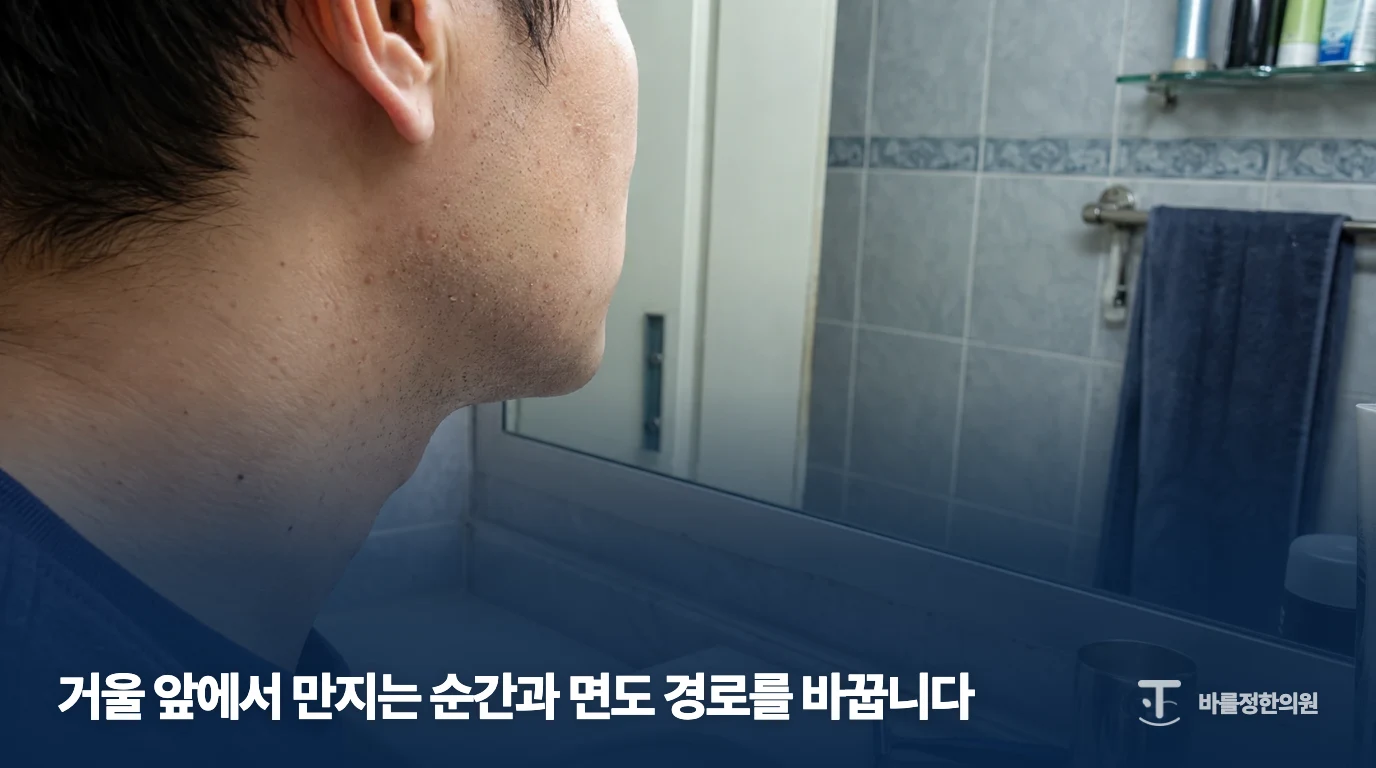 거울 앞에서 볼과 턱의 돌기를 살펴보는 남성의 모습